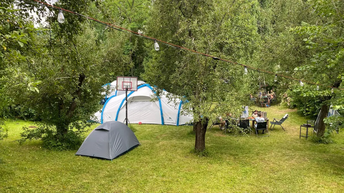 Corturi așezate sub copaci, în poiana taberei