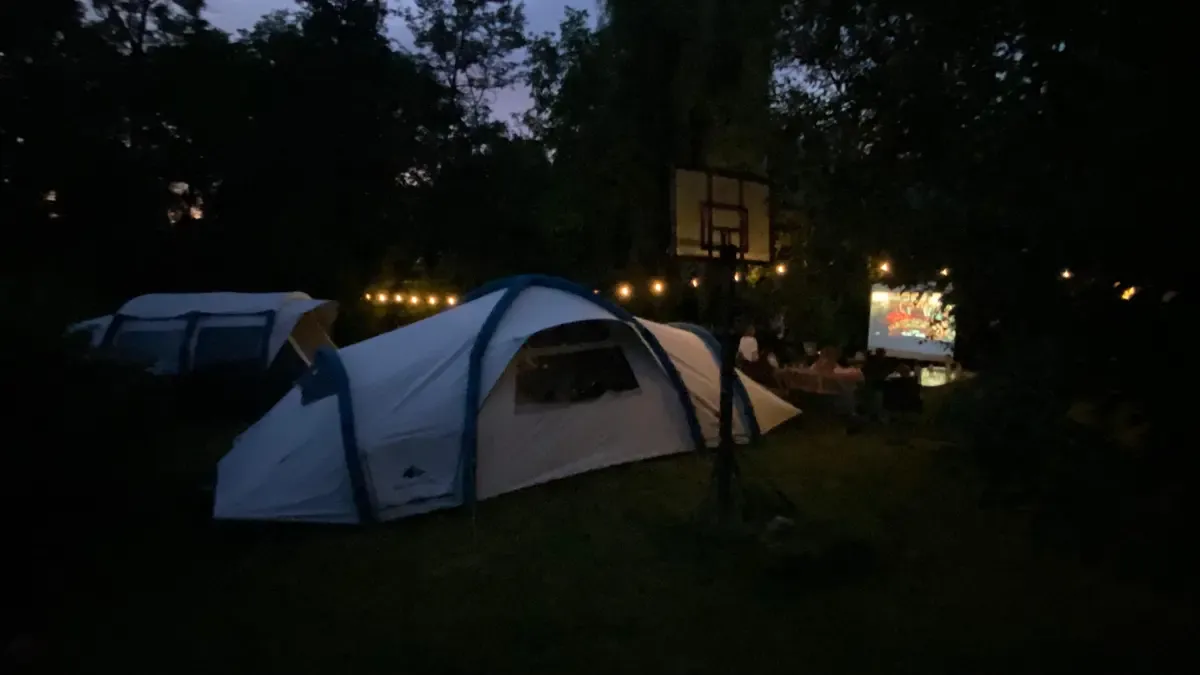Cort în amurg, cu luminile taberei în fundal